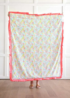 Dainty Floral Pastel Blanket featuring small yellow, pink, blue, and coral flowers on a white background with coral satin ruffle.
