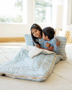 Two kids smiling sitting on a soft light blue Minky Couture sleeping bag.