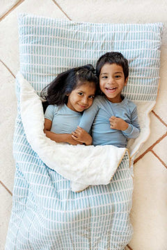 Two kids smiling lying on light blue Minky Couture Dash sleeping bag.