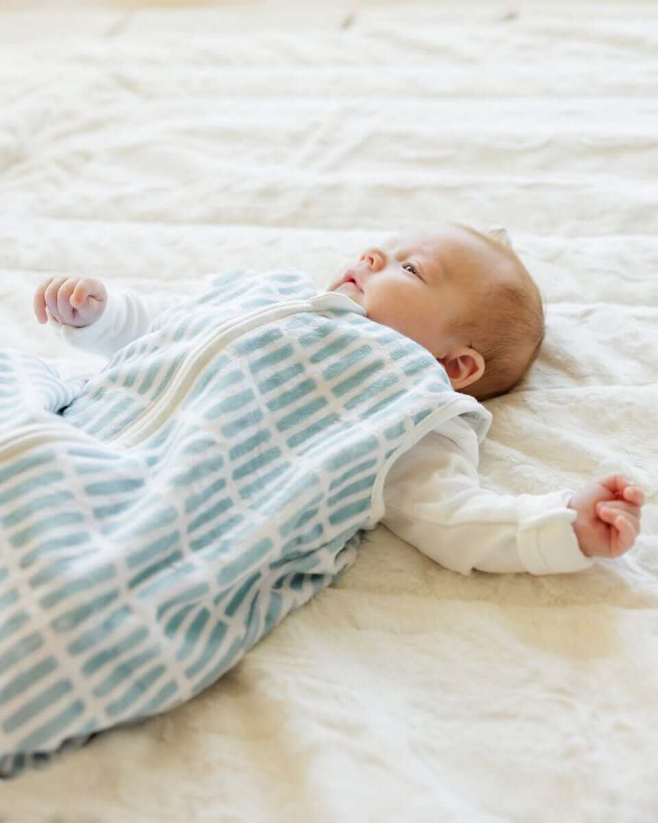 Baby lying on soft cream blanket, with Dash Wearable Minky Blanket.