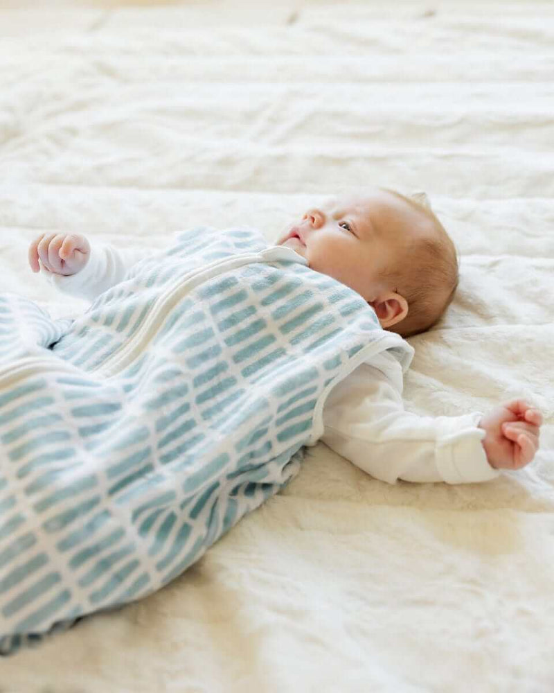Baby lying on soft cream blanket, with Dash Wearable Minky Blanket.
