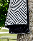 Everywhere Blanket Black Geo hanging on a tree, showcasing its geometric black pattern and plush black interior.