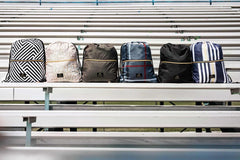 Five stylish Minky Couture backpacks displayed on bleachers in various patterns and colors.