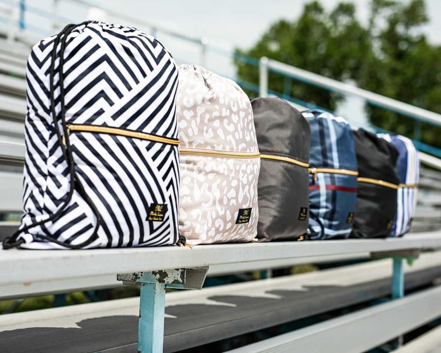 Assorted stylish backpacks with geometric patterns displayed on bleachers, perfect for school and outdoor activities.