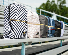 Assorted stylish backpacks with geometric patterns displayed on bleachers, perfect for school and outdoor activities.