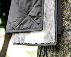 Everywhere Charcoal Blanket hanging on a tree, showcasing the plush interior and water-resistant exterior.