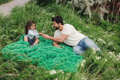Father and daughter enjoying the Ultra Sorbet Kelly Green weighted blanket on a grassy outdoor setting.