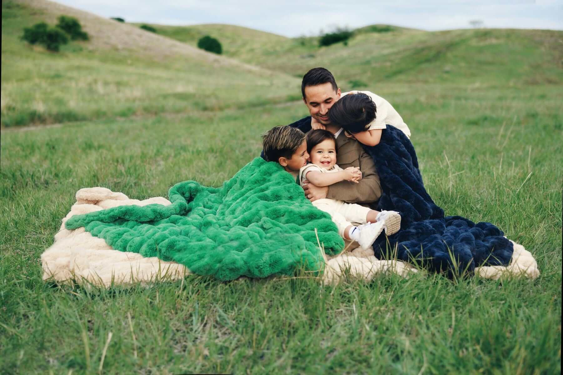 Family enjoying the Minky Couture Ultra Sorbet weighted blankets outdoors in a grassy field.