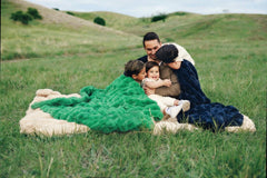 Family enjoying the Minky Couture Ultra Sorbet weighted blankets outdoors in a grassy field.