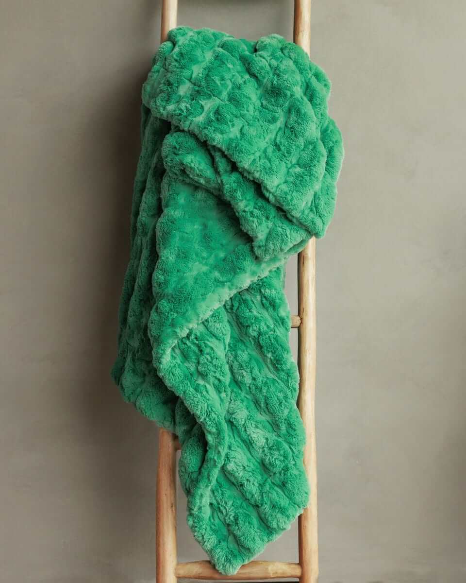Ultra Sorbet Kelly Green weighted blanket draped over a wooden ladder, showcasing its plush texture and vibrant green color.