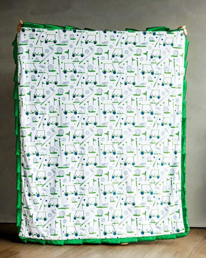 Tee-Time Blanket with fun golf-themed print on a soft blue background and green plush backing.