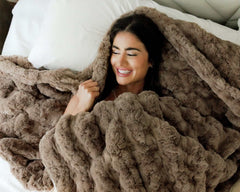 Woman smiling while wrapped in the Ultra Sorbet Gingersnap Blanket, showcasing its soft faux fur texture.