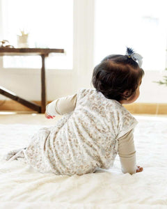 Back of a baby sitting on a soft cream blanket, with a Forget Me Not floral Wearable Minky Blanket.