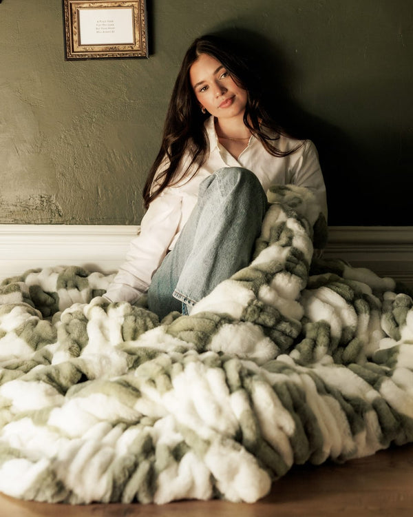 A cozy scene featuring the Hugs Check Sage Blanket, showcasing its soft texture and gentle sage hues.