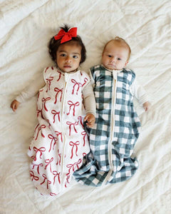 Two babys lying on a soft bed with Minky Couture wearable blankets.