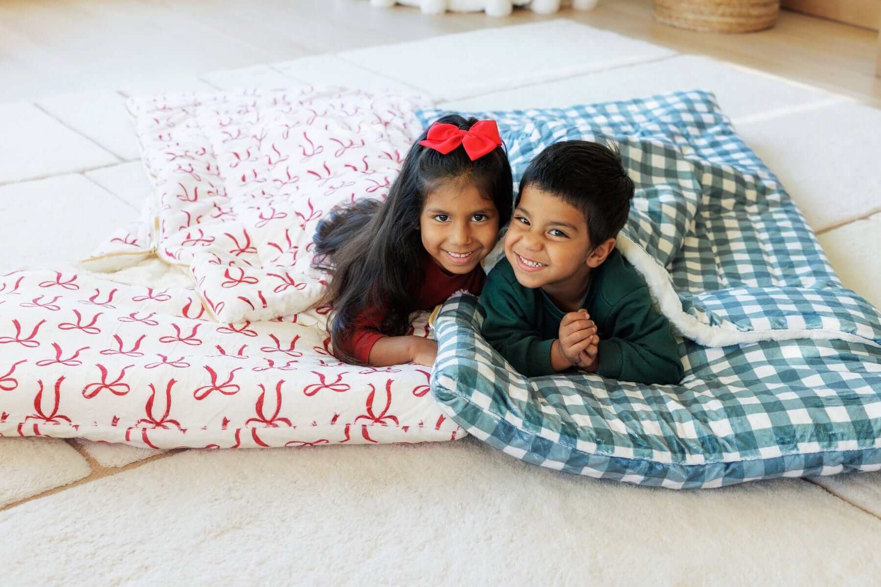 2 children under red bow and gray gingham Minky Couture sleeping bags