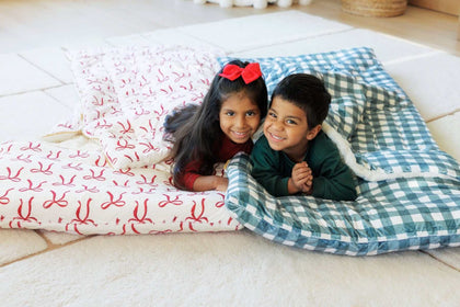 2 children under red bow and gray gingham Minky Couture sleeping bags