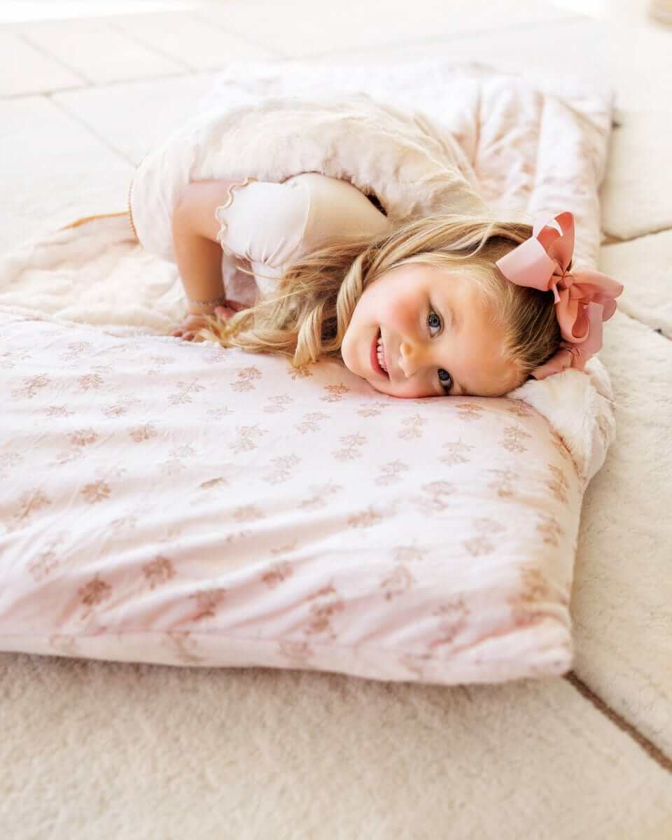 Girl with pink bow lying on a pink floral Minky Couture Sleeping Bag Hampton Blooms.