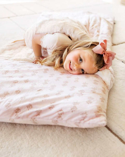 Girl with pink bow lying on a pink floral Minky Couture Sleeping Bag Hampton Blooms.