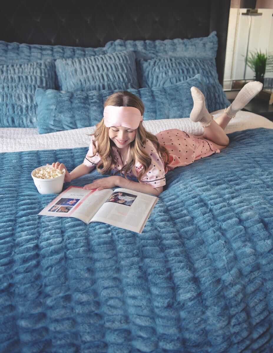 Girl reading on a bed with plush Minky Couture Hugs Denim Sham.