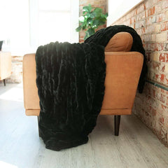 Hugs Black Blanket draped over a modern sofa, showcasing its plush texture and cozy aesthetic.