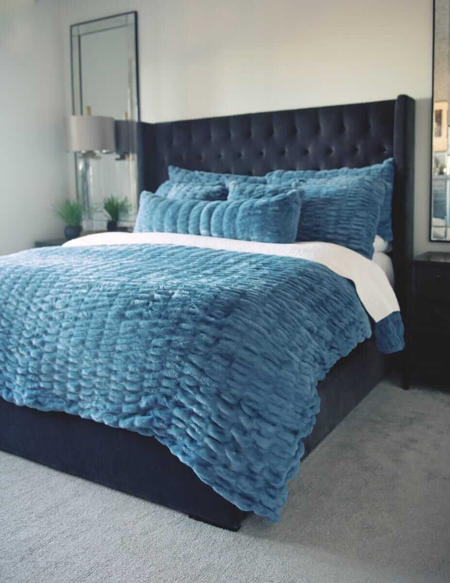 Bedroom with a bed featuring blue Hugs Denim Sham bedding and pillows.