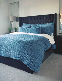 Bedroom with a bed featuring blue Hugs Denim Sham bedding and pillows.