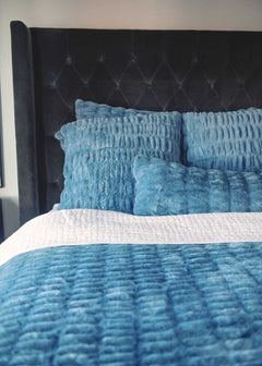 Blue textured Minky Couture Hugs Denim Sham bedding set on a bed with a tufted black headboard.