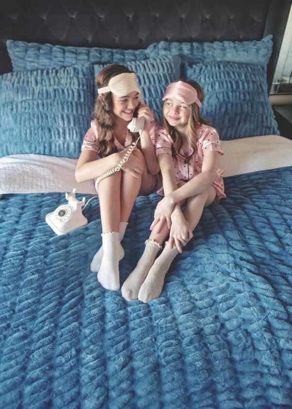 Two girls sitting on a bed with Minky Couture Hugs Denim Duvet.
