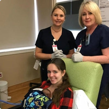 Health professionals smiling with a new mother and her baby in a hospital setting, highlighting support and care.