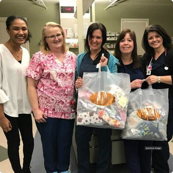 Group of healthcare professionals smiling and holding bags filled with fabric donations.
