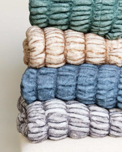 Minky Couture Hugs Blankets in a stack with different colors showcasing faux fur texture and cozy design.