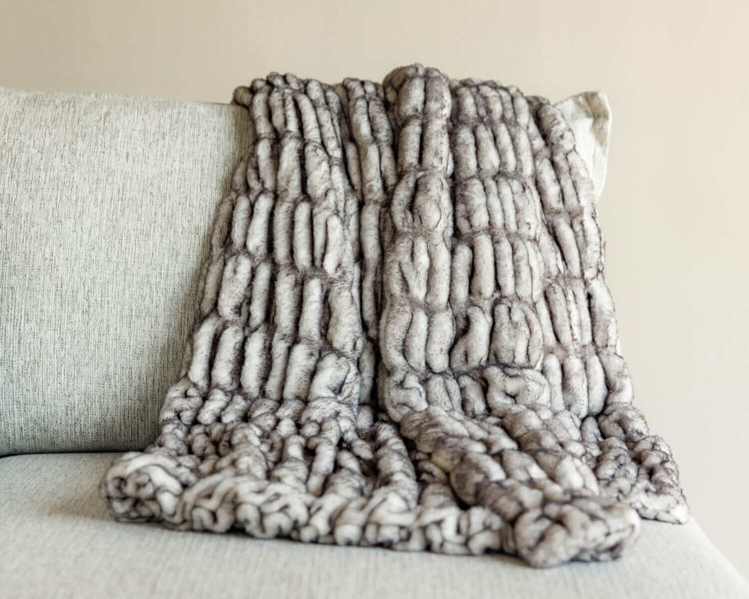 Hugs Obsidian Blanket draped on a couch, showcasing its plush faux fur texture and unique frosted design.