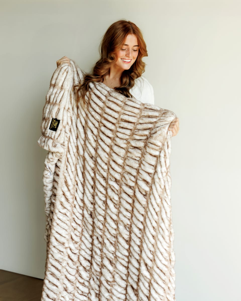 Hugs Topaz Blanket, a cozy faux fur blanket in warm tan, providing plush softness and inviting warmth.