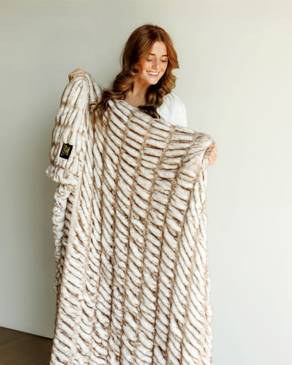 Hugs Topaz Blanket, a cozy faux fur blanket in warm tan, providing plush softness and inviting warmth.