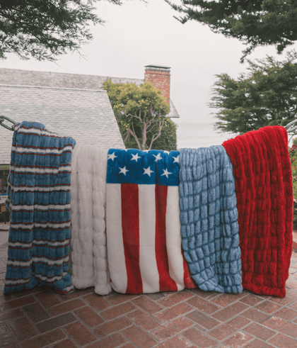 Colorful blankets displayed outdoors, featuring patriotic red, white, and blue patterns, perfect for cozy warmth.