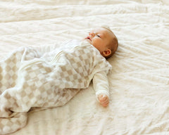 Baby lying on a soft blanket, with a Oat Check Wearable Minky Blanket.