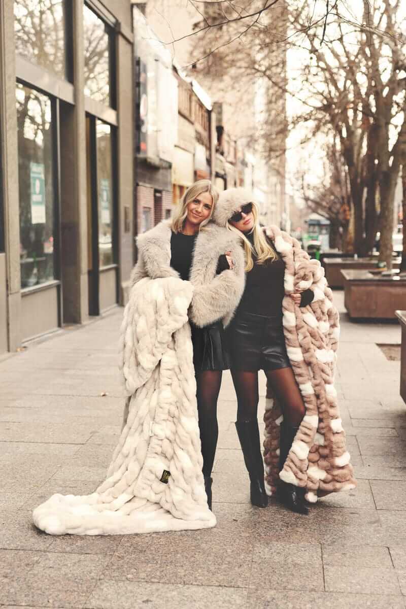 Two women wrapped up in two Minky Couture blankets standing on a city street.