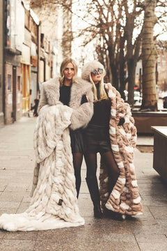 Two women wrapped up in two Minky Couture blankets on a city street.