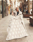 Woman holding a cream and white Hugs Polka Dot Toasted Marshmallow Blanket in the city.