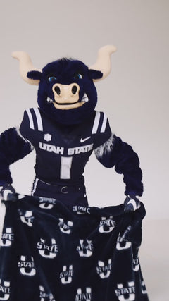 Utah State Aggies mascot holding blue and white Minky Couture collegiate blankets in a studio setting.