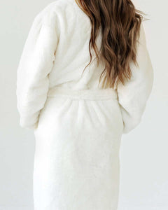 Back view of a woman wearing a warm and cozy Cream Robe with a plush texture and waist tie.