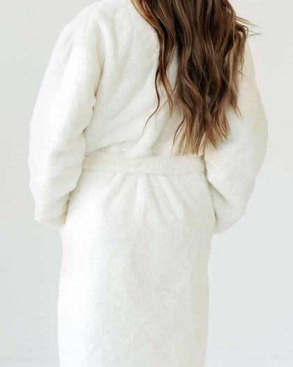 Back view of a woman wearing a warm and cozy Cream Robe with a plush texture and waist tie.