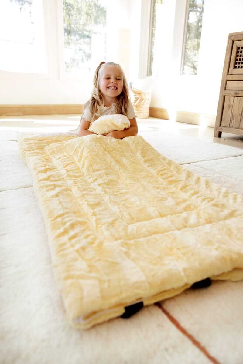 Happy girl with Minky Couture Sleeping Bag Butter Yellow in home light living room.