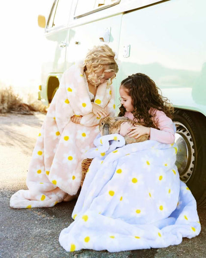 Two girls wrapped in blankets, Lush Peach and Lilac Flower Blankets, enjoying a cozy moment outdoors.