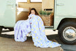 Child wrapped in Minky Couture Lush Lilac Flower Blanket with playful floral design by a vintage van.