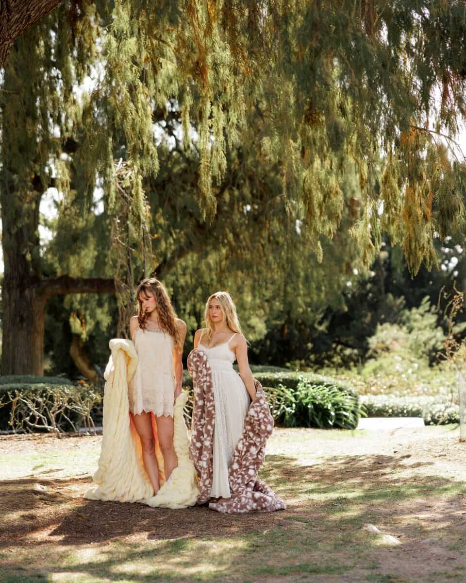 Minky Couture Lush Butter Yellow Floral Blanket showcased by two women outdoors in a sunlit garden.