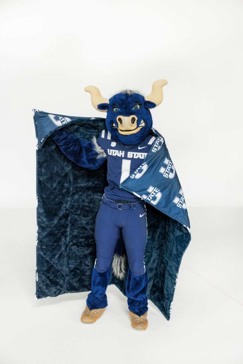 Utah State Aggies mascot wearing Minky Couture Utah State Aggies navy blanket with hood indoors.