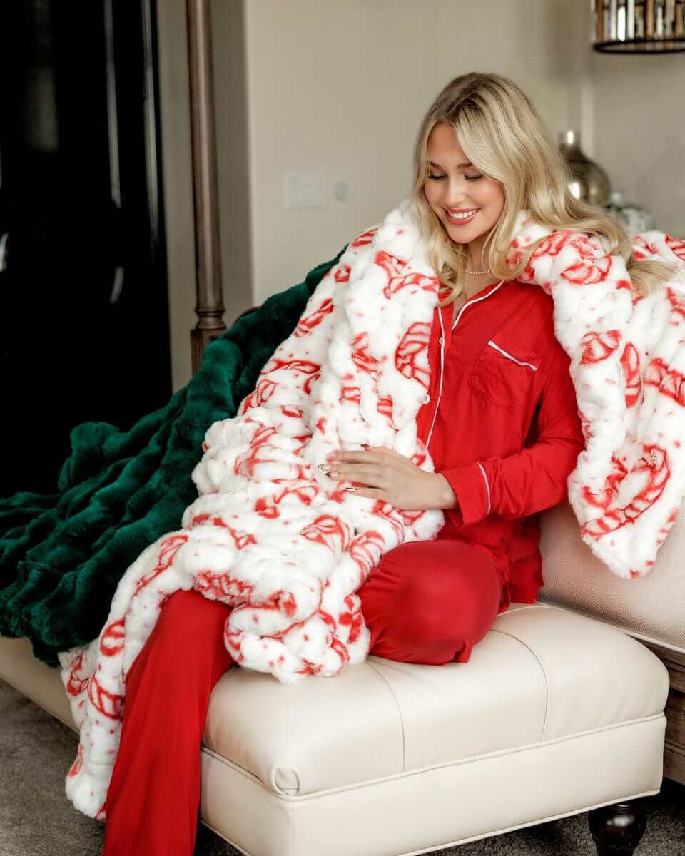 Woman sitting with a green and a white and red peppermint Hugs Candy Cane blankets
