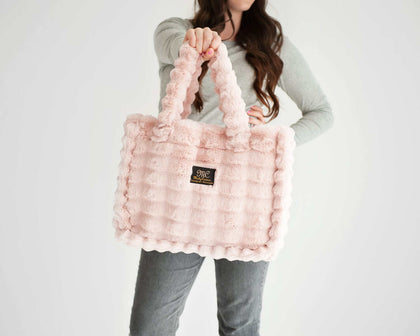 Ripple Blush Annie Bag, a luxurious pink handbag held by a woman, showcasing its stylish design and texture.